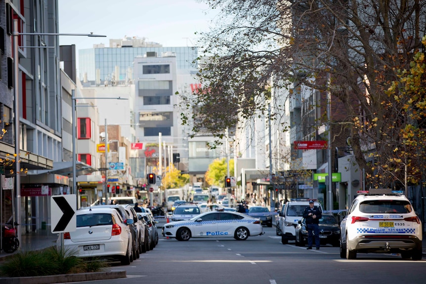 Busy city street with police cars blocking off crime scene in Sydney's Bondi Junction 