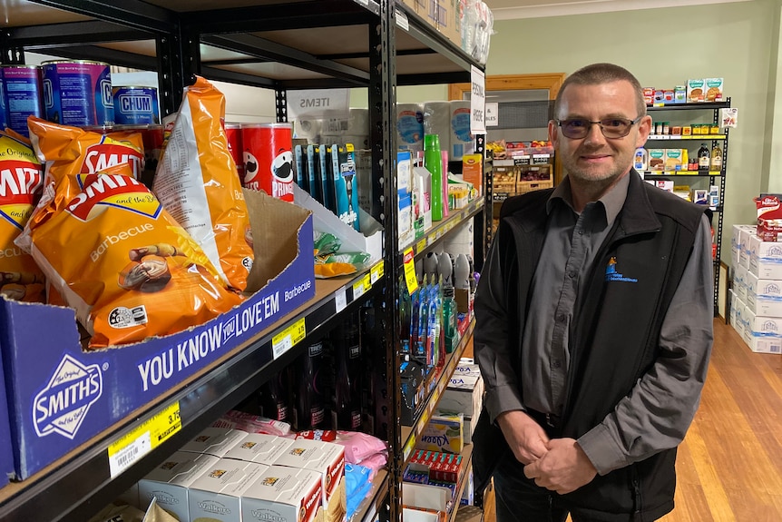 Gary Barnes stands in the community centre shop among a shelf of chips and toiletries.
