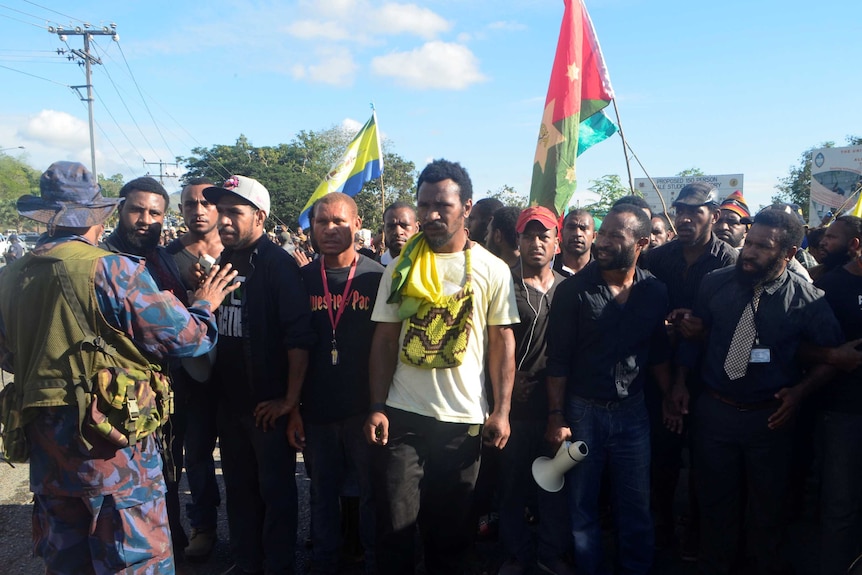 A police officer prevents students from marching from the University of Papua New Guinea.