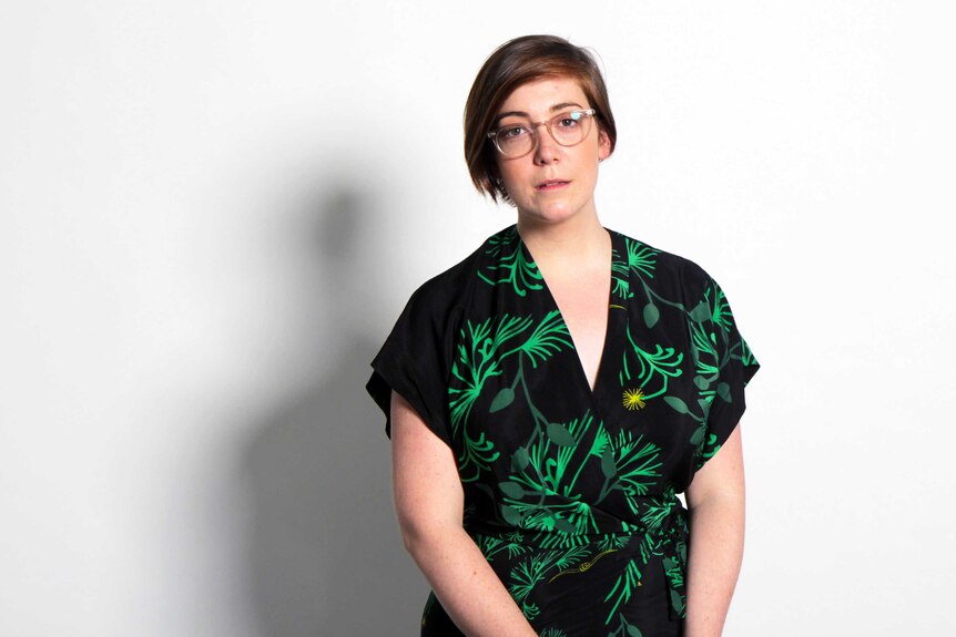 A woman wearing a green dress and glasses