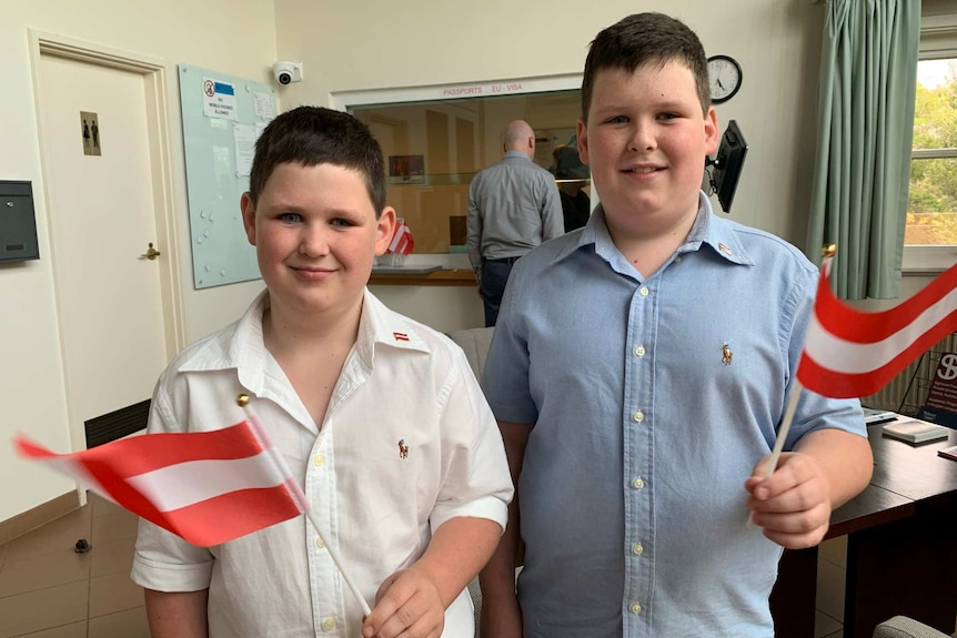 Callum and Ethan smile while holding Austrian flags.