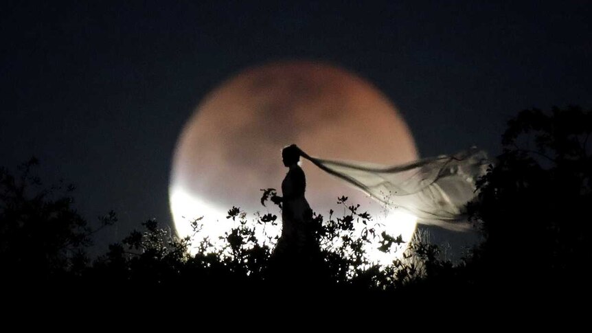 A bride poses for photo during a total lunar eclipse from in Brasilia, Brazil.