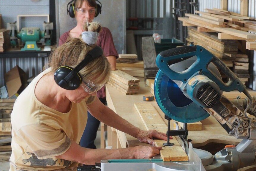 Women cutting wood in a workshop.
