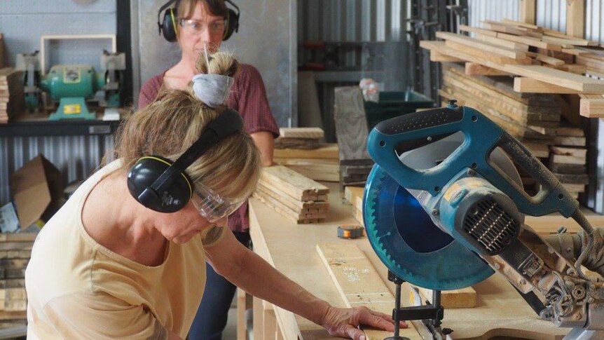 Women cutting wood in a workshop.