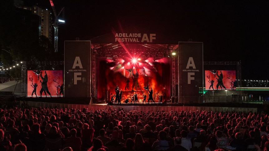 A concert venue with dancers and red lighting