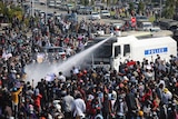A white truck marked "Poilce" sprays water at a crowd of people.