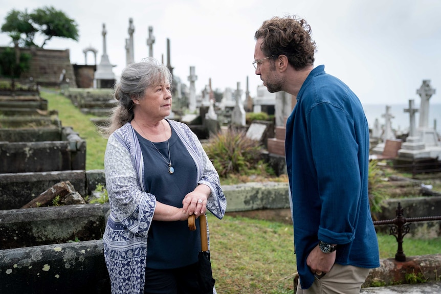 Noni Hazelhurst and Rafe Spall, a young man speaking to an older woman in a cemetery, in the film Long Story Short