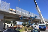 Workers start removing the screens along the overpass at South Road.