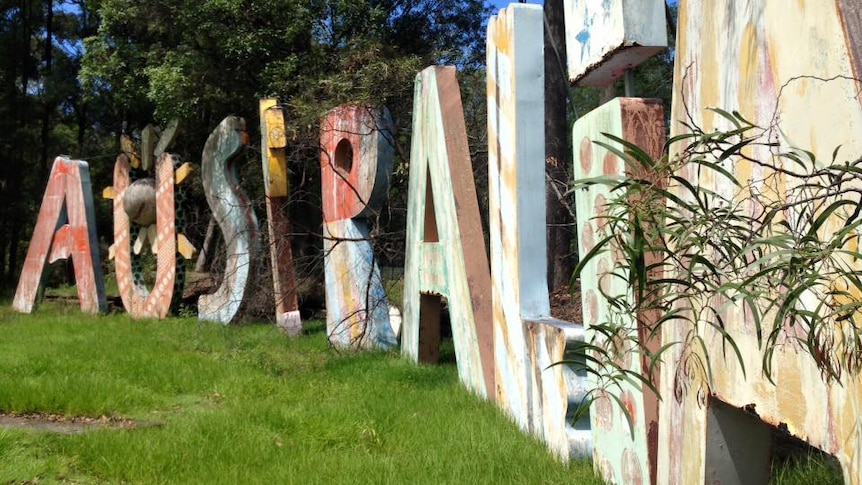 A faded Expo 88 'Australia' sign in an overgrown cow paddock.