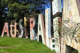 A faded Expo 88 'Australia' sign in an overgrown cow paddock.