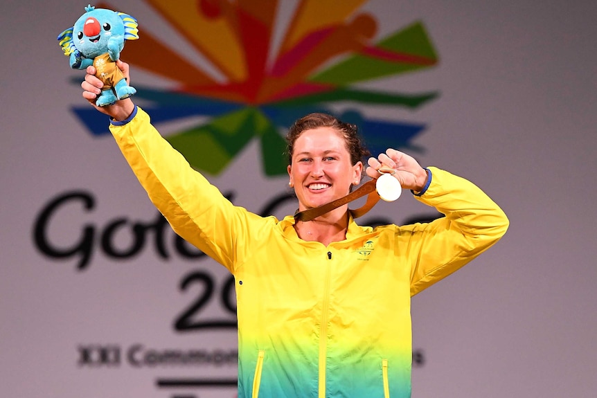 Weightlifter Tia-Clair Toomey lifts her medal and games mascot