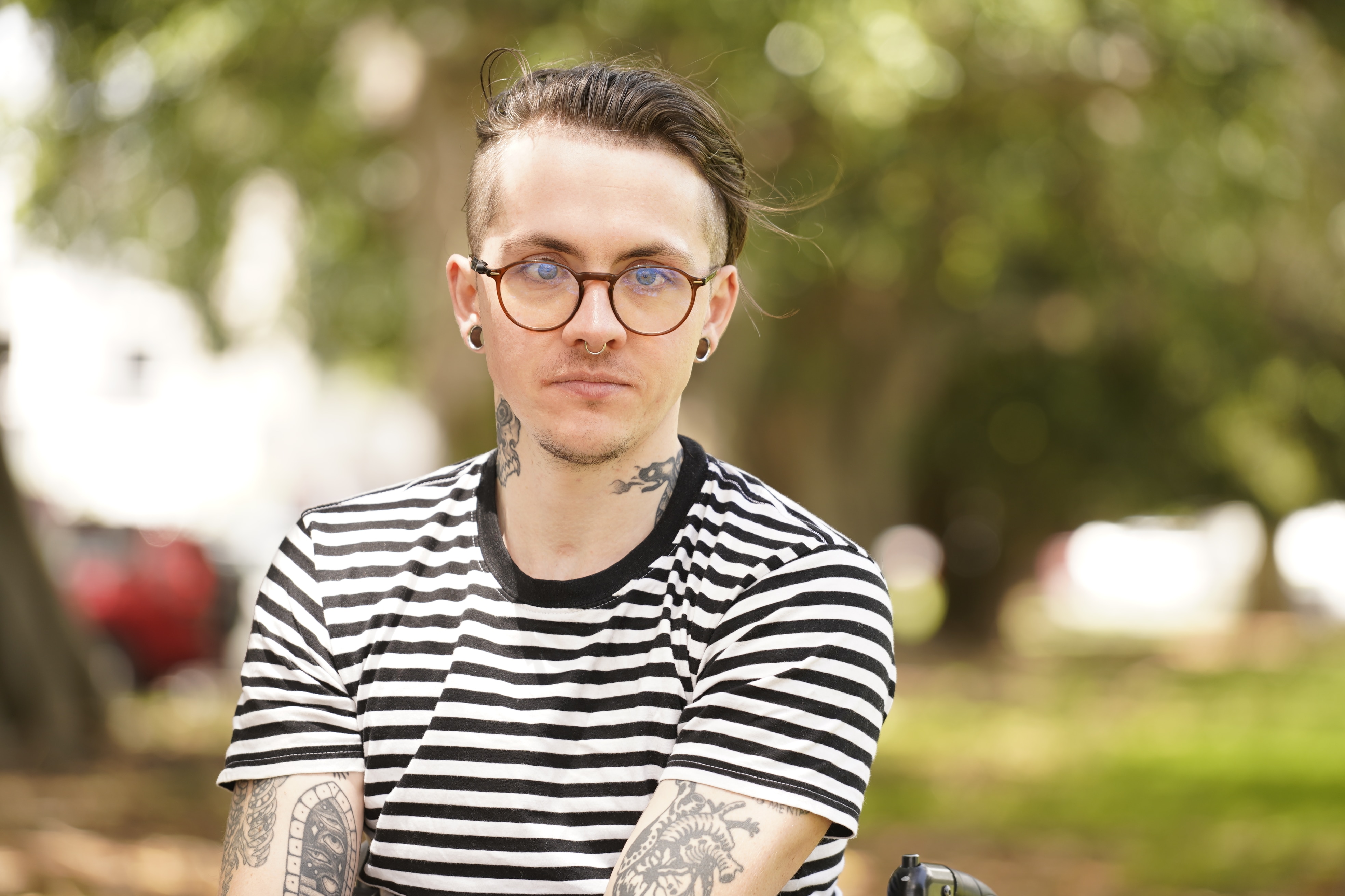 A close up of a man, Az Cosgrove. He is wearing a striped shirt and wearing glasses.