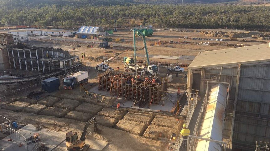 Aerial view of construction site, showing a steel structure, trucks and lots of dirt bordering a sugar mill