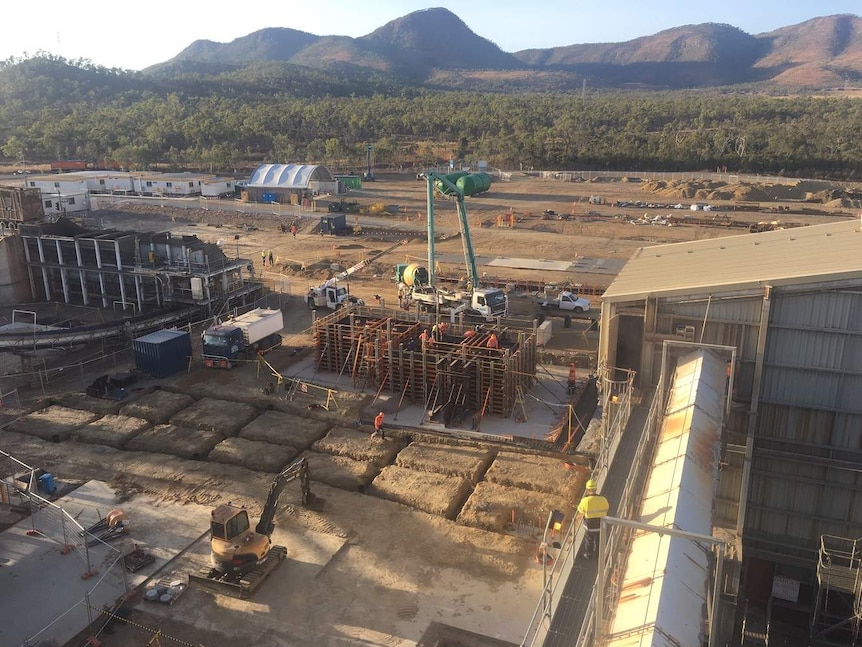 Aerial view of construction site, showing a steel structure, trucks and lots of dirt bordering a sugar mill