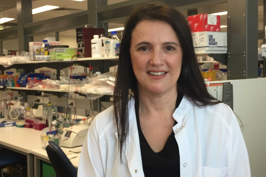 A woman wearing a lab coat in a medical lab.