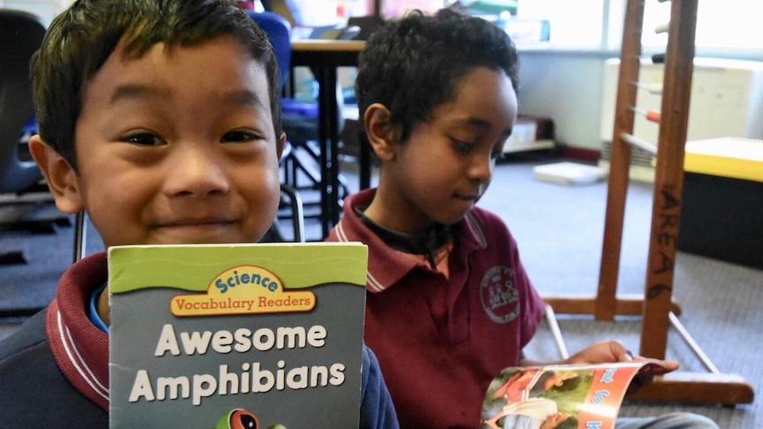 Two students read books in their classroom.