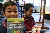 Two students read books in their classroom.