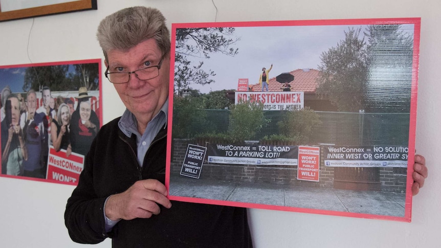 Chris Eleanor holds up a photograph of him protesting the WestConnex