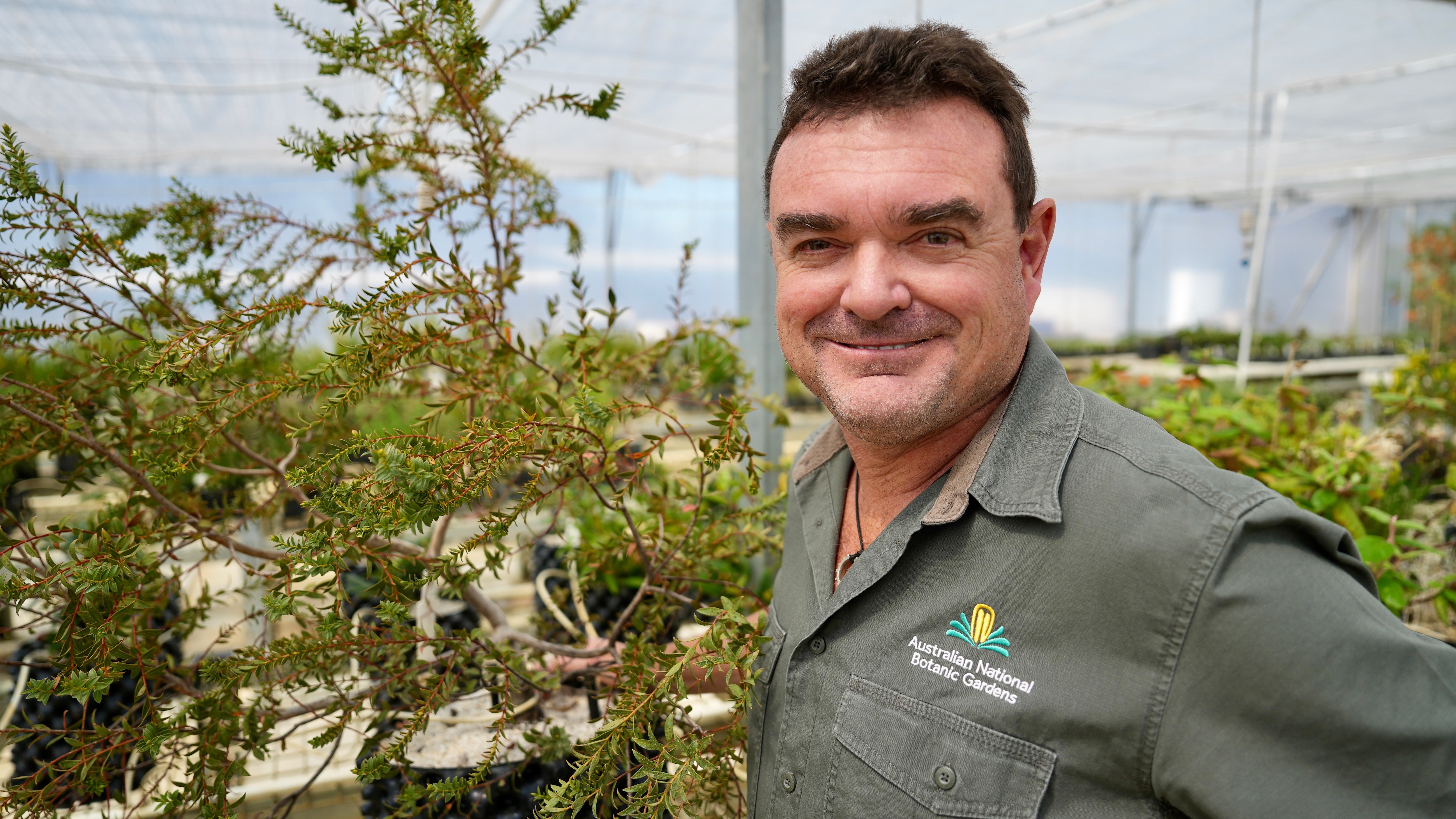 A professional smiles at the camera near trees he has helped to grow.