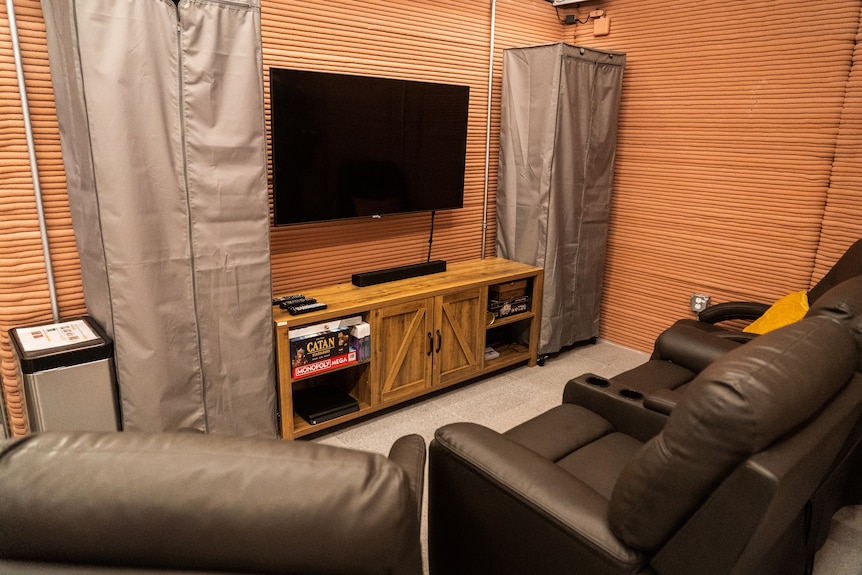 A space with a flat screen television, board games and three big lounge chairs.