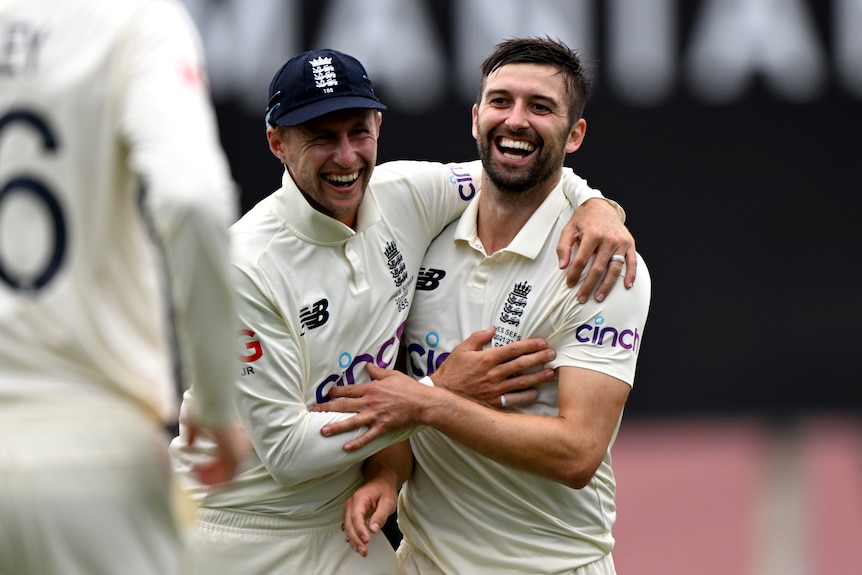 England cricketers Joe Root and Mark Wood hug and smile during an Ashes Test against Australia.