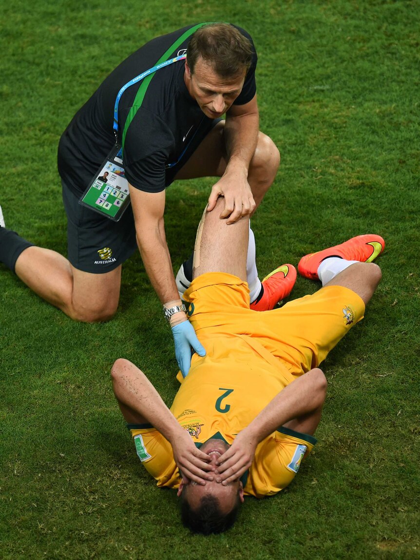 A trainer checks on Australia's Ivan Franjic against Chile in Cuiaba at the 2014 World Cup.