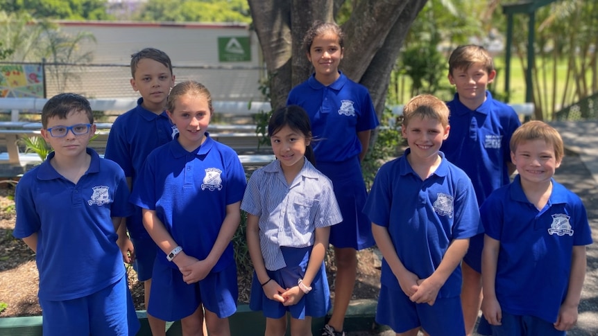 Students from Dutton Park State School stand in a group, smiling. They are wearing blue uniforms.
