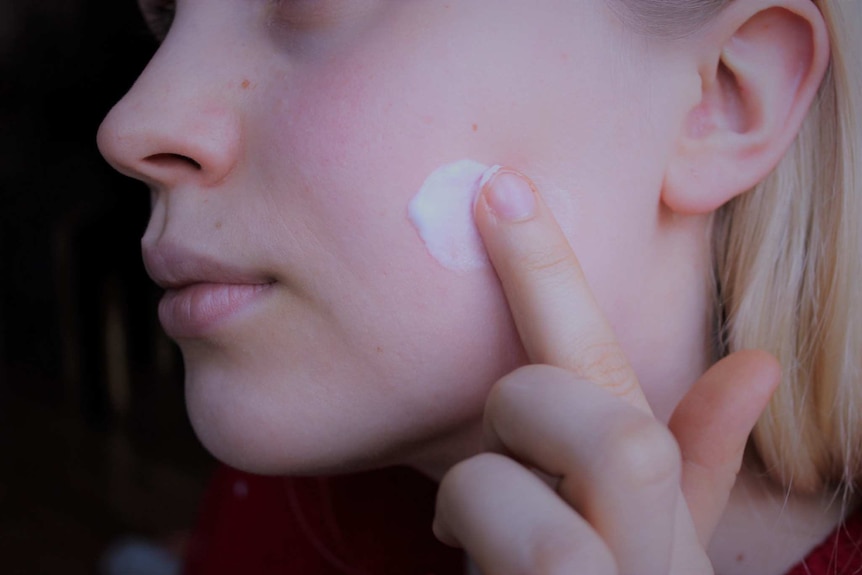 A woman puts a cream on her face