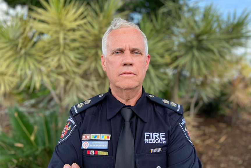 a fire safety manager in uniform looks directly into the camera with his arms folded