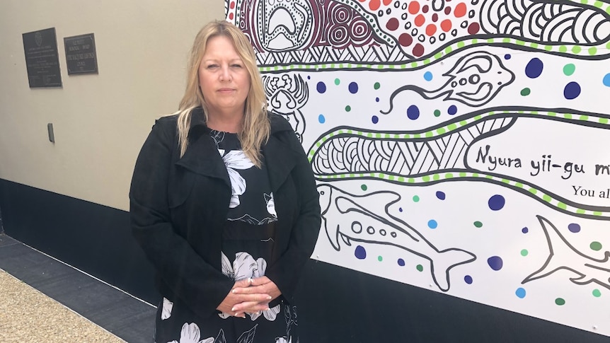 A woman standing in front of indigenous painting.