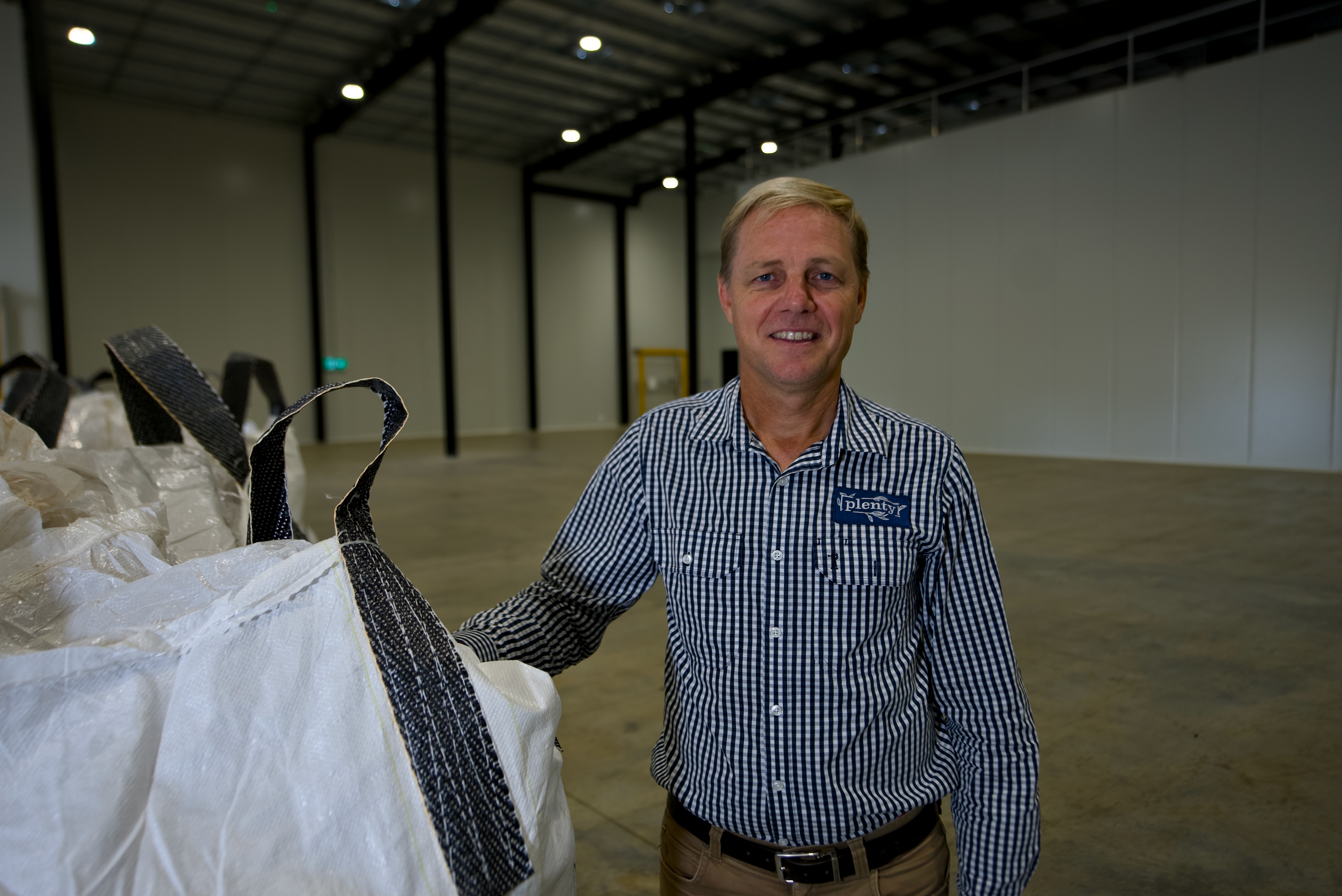 An older man standing next to large industrial bags.