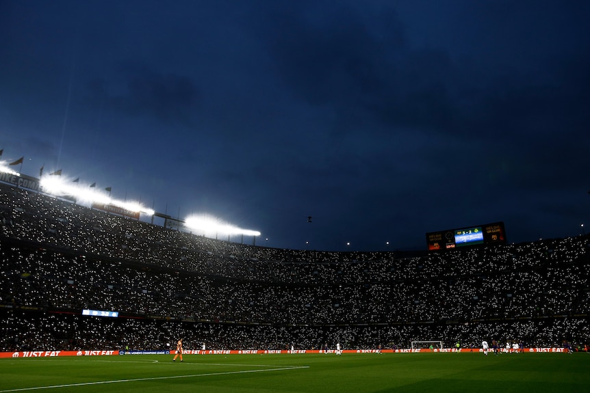 Dots of light can be seen from the stands in a stadium as fans use lights from their mobile phones