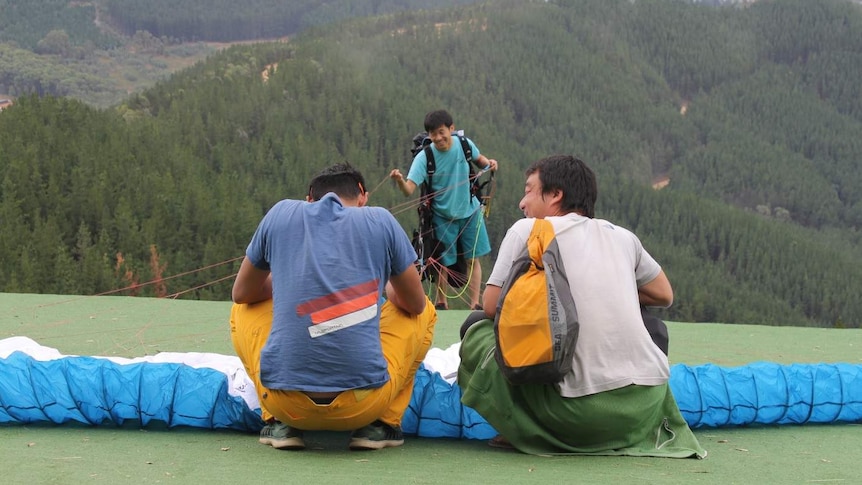 Three men work to prepare a competitor who is about to launch off Mystic Hill