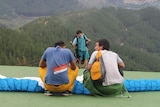 Three men work to prepare a competitor who is about to launch off Mystic Hill