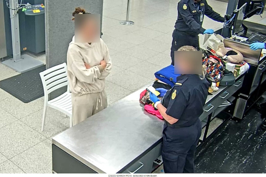 A woman, whose face is blurred, speaks to border agents at Perth airport.