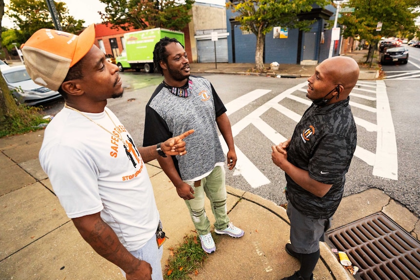 Three men chatting on a street corner in Baltimore