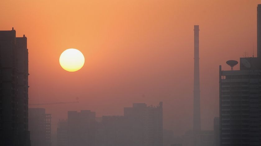 A layer of pollution hovers over Beijing as the sun rises.