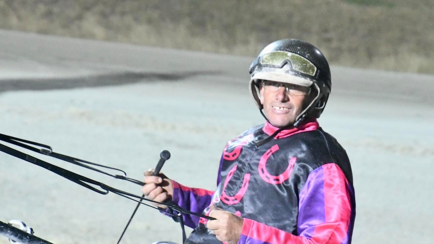 A man smiles after a harness race.