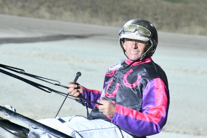 A man smiles after a harness race.