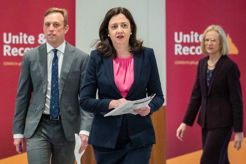 Queensland's Premier and Health Minister leaving a media conference, followed by the state's Chief Health Officer