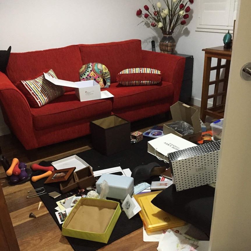 Boxes and papers strewn on a loungeroom floor after it has been ransacked by theives.