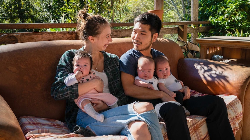 Samara and Uram and their triplets sit on a couch outside, for a story about what it's like having surprise triplets.