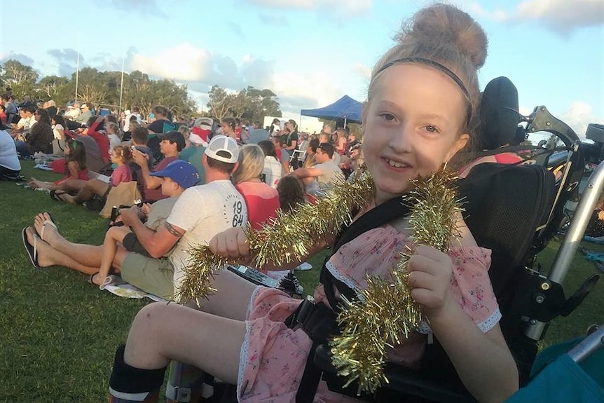 Portrait of girl in wheelchair with tinsel around her neck