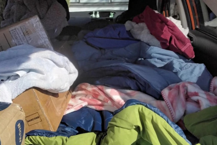 Piles of blankets and cardboard boxes in the back of a car