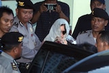Schapelle Corby, with her covered her head with a scarf, is surrounded by Indonesian police.