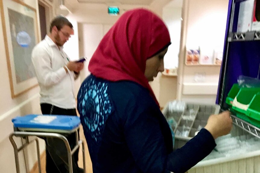 A Muslim nurse and a Jewish father stand in a hospital corridor.