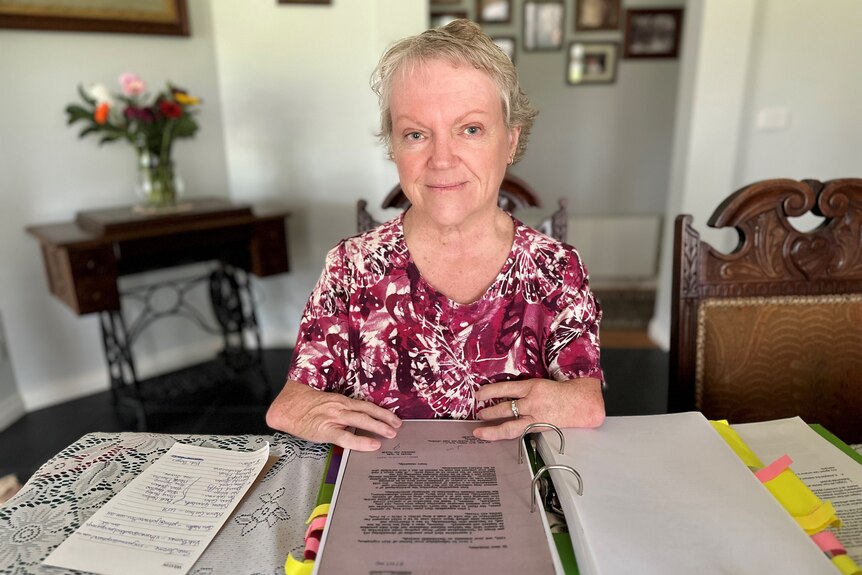 A photo of thalidomide survivor Lisa McManus sitting at a table with paperwork