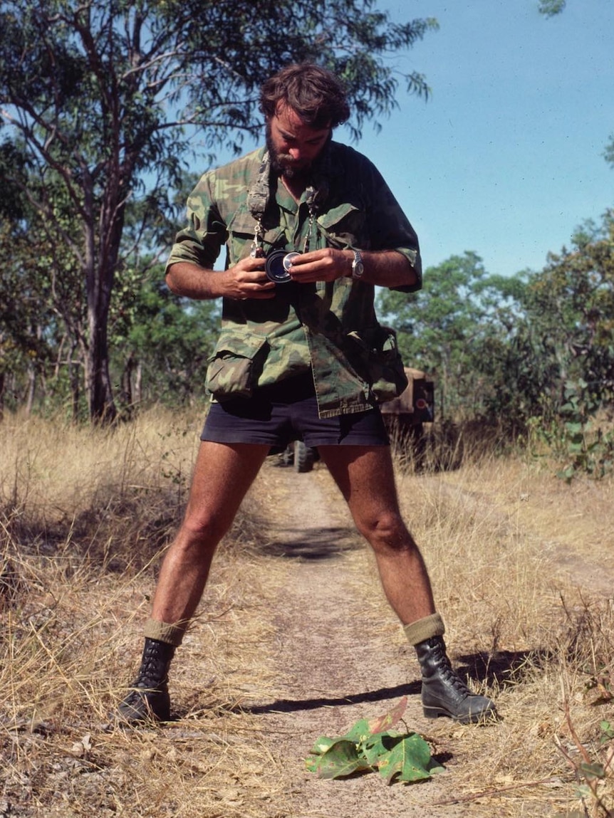 Les Hiddins stands over a Kakadu plum to photograph it.