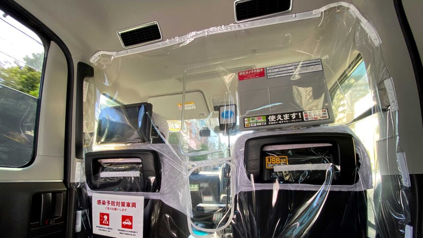 The inside of a Japanese taxi with a plastic screen separating the front from the back