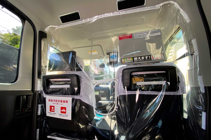 The inside of a Japanese taxi with a plastic screen separating the front from the back